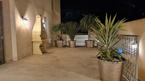 Un patio con plantas en macetas, un muro decorativo y una reja de metal.