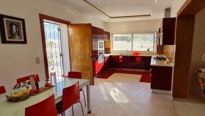 Una cocina moderna con una decoración en rojo y negro, un área de comedor con sillas rojas y un amplio ventanal que proporciona luz natural.