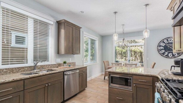 A modern kitchen with dark wood cabinets, a stainless steel dishwasher, and a built-in oven.