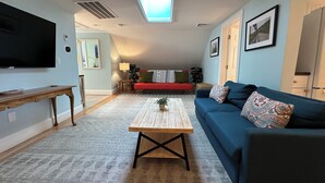 Ein Wohnzimmer mit Fernseher, einer Couch, einem Couchtisch und einem Dachfenster.