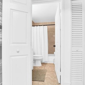 Een badkamer met een toilet, douchegordijn en een beigekleurige vloer.