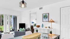 Ein modernes Wohnzimmer mit einem Glastisch, grauen Sofas und einer weißen Tür.