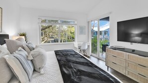 Een moderne slaapkamer met een bed, een televisie, een bureau en uitzicht op de omgeving.