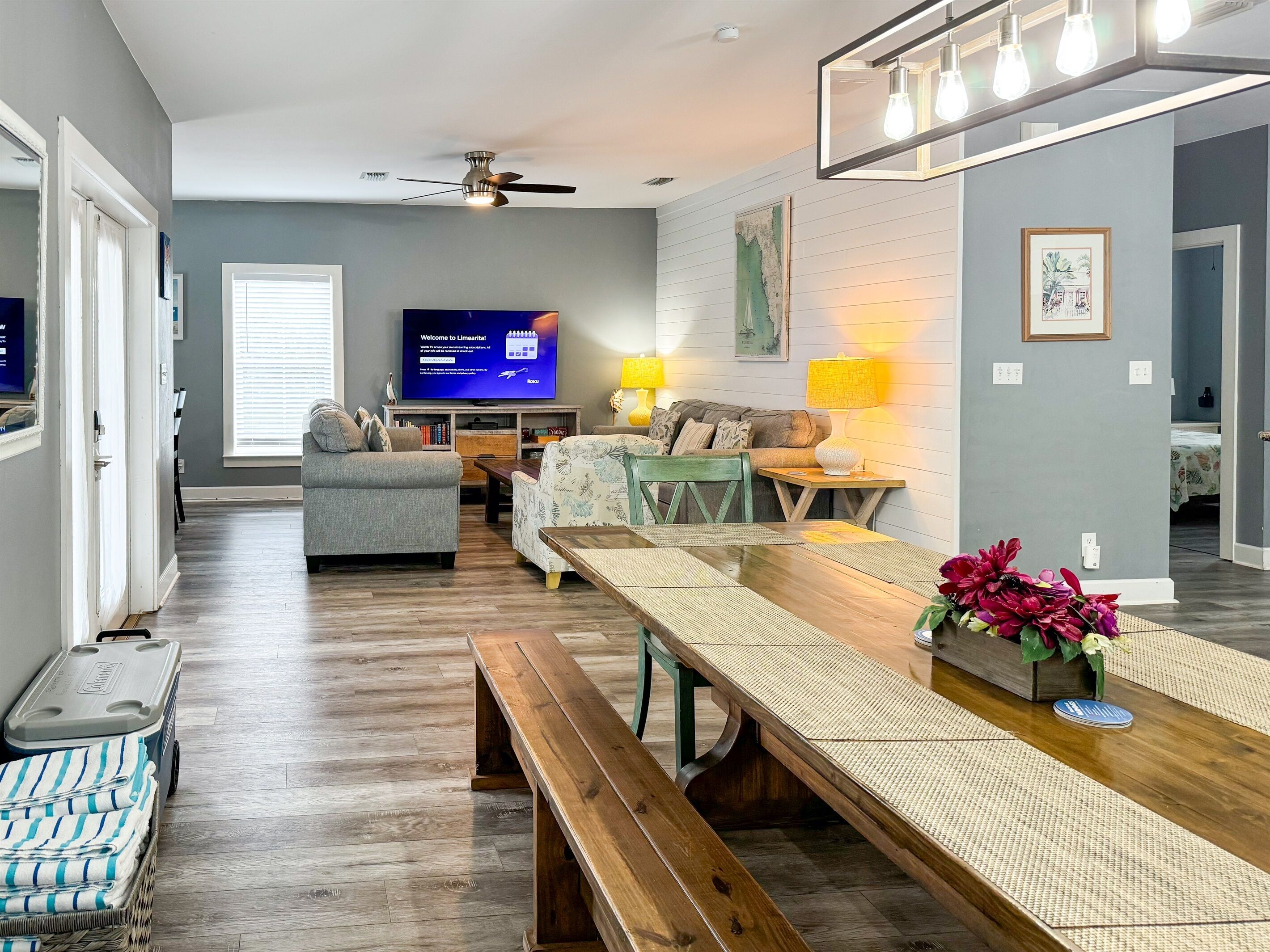 A modern living room with a wooden bench, a television, and a ceiling fan.
