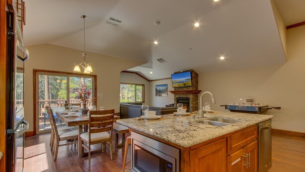 A spacious kitchen with a large island, wooden cabinetry, and a stone fireplace. - AC, Custom Bunks, Bubble Hockey, Sauna, Walk to Heavenly/ Lake, Grill – Tahoe Woods Paradise (South Lake Tahoe)