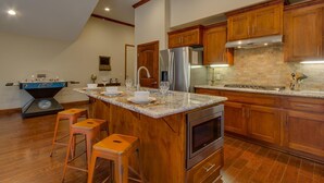 A kitchen with wooden cabinets, a stainless steel refrigerator, a built-in oven, and a foosball table. - AC, Custom Bunks, Bubble Hockey, Sauna, Walk to Heavenly/ Lake, Grill – Tahoe Woods Paradise (South Lake Tahoe)