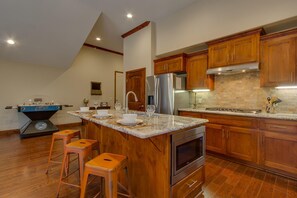 Una cocina con armarios de madera, un refrigerador de acero inoxidable, horno empotrado y mesa de fútbol.