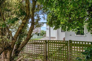 A fenced outdoor area with trees and a building in the background.