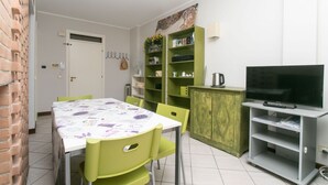 A dining area with a table, chairs, a television, and a bookshelf. - S232 - Sirolo, delightful two-room apartment with terrace (Sirolo)