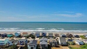 A coastal residential area with houses close to the beach, featuring a variety of house designs and a clear view of the ocean.
