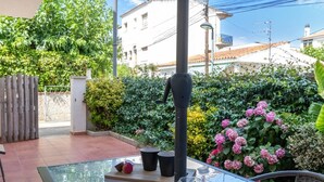 A patio with a glass table, potted plants, and a metal fence.