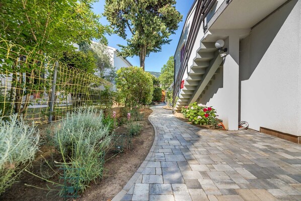 A paved pathway leading to a building with a white exterior and a staircase.