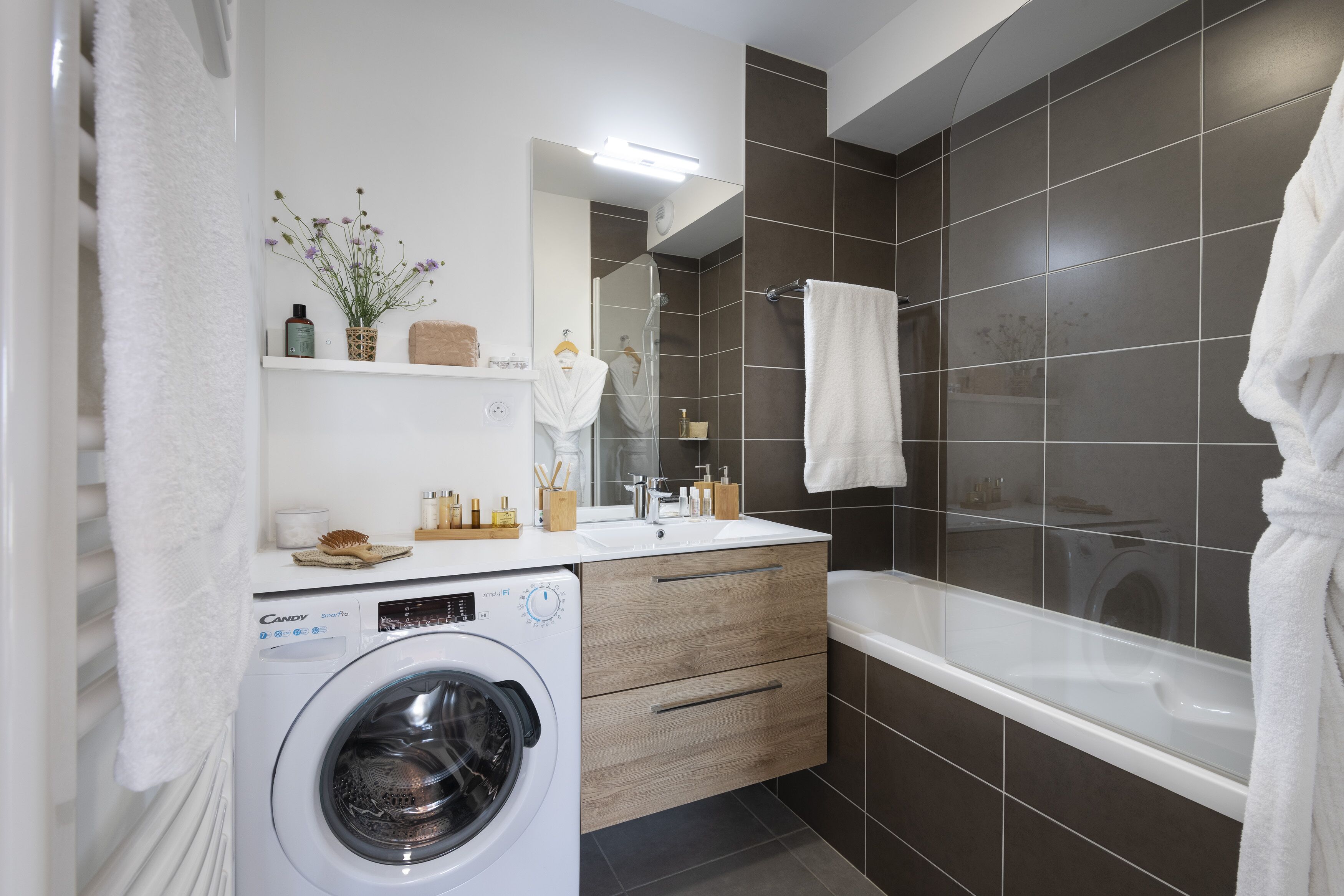 A modern bathroom with a washing machine, a sink, and a bathtub.