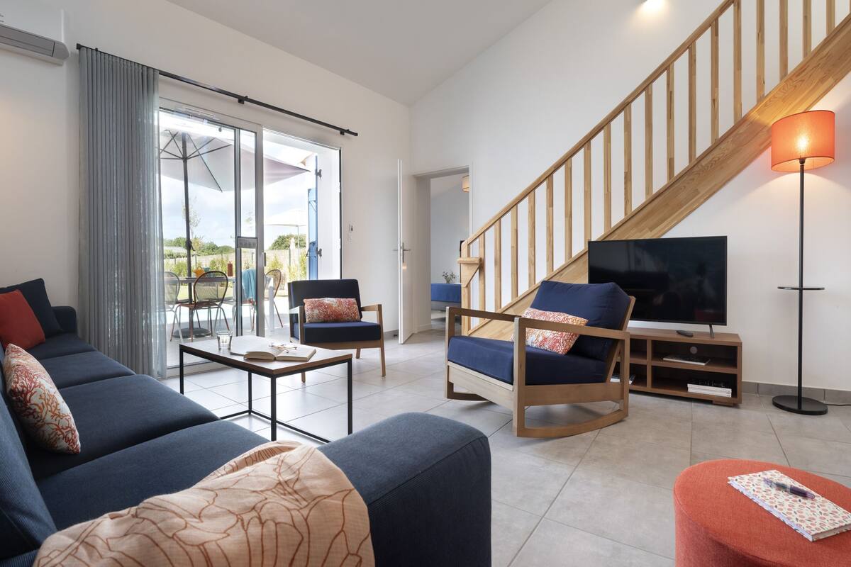 Una sala de estar moderna con un sofá, sillones, una mesa de centro y un televisor.