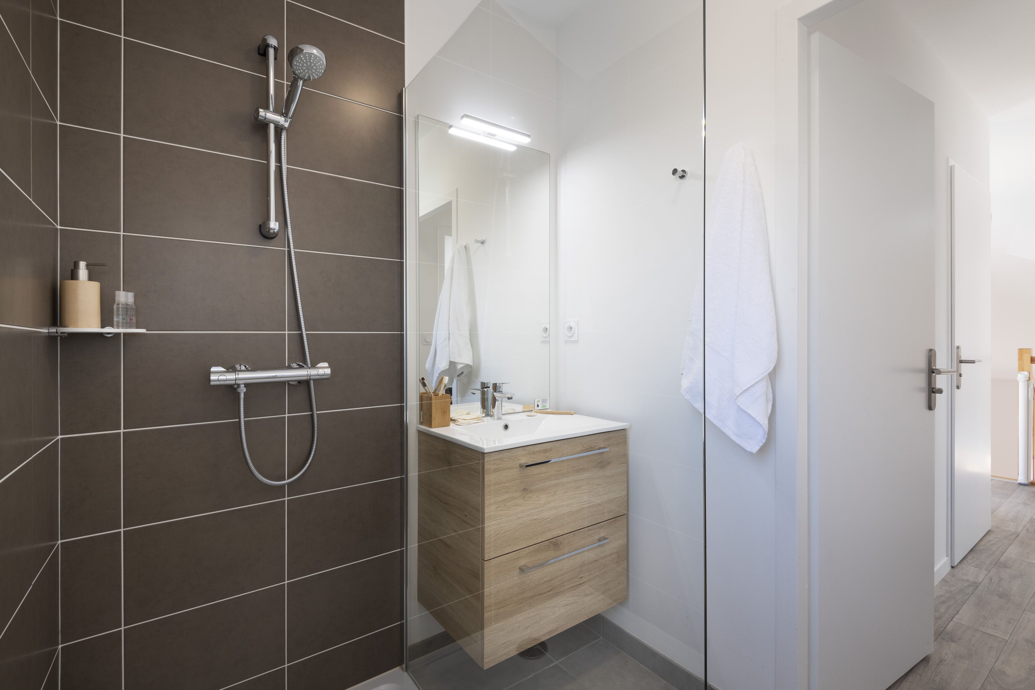 A modern bathroom with a shower, a sink, and a mirror.