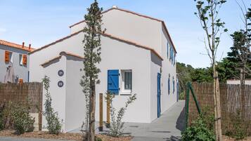 A white building with blue shutters, numbered 21 and 22, surrounded by a bamboo fence and small plants.