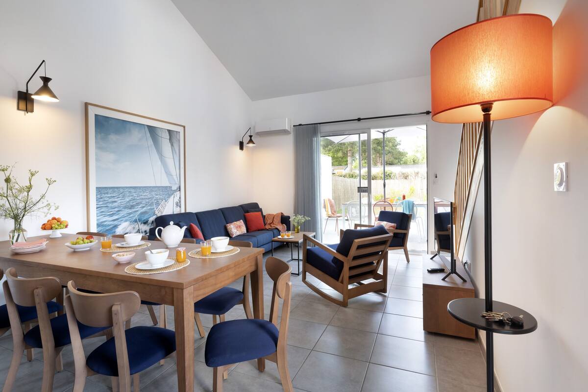 Una sala de estar moderna con comedor, que incluye un sofá, sillas, una mesa de centro y un cuadro grande.