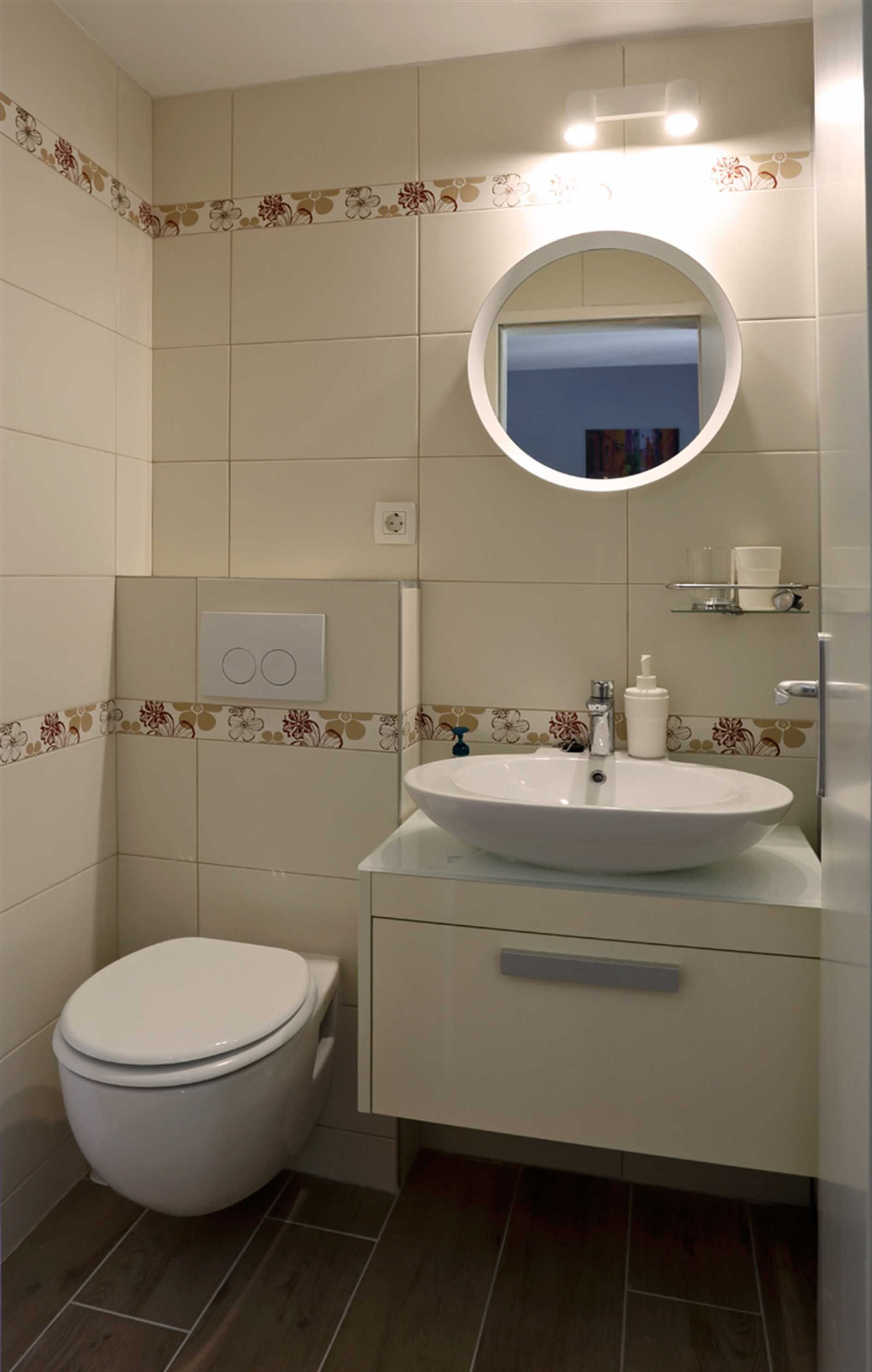 A bathroom with a toilet, a sink with a mirror above it, and a shelf with toiletries.