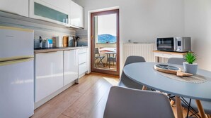 Una cucina moderna con mobili bianchi, forno a microonde integrato e zona pranzo con tavolo e sedie.