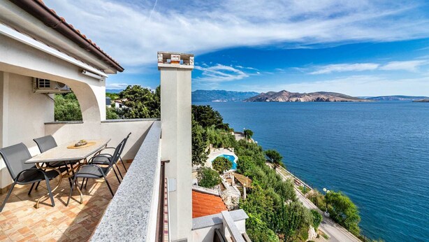Una terrazza con mobili da esterno, una piscina e una vista panoramica su un lago e montagne.