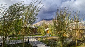 A rustic lodge with stone pathways and wooden structures amidst a mountainous landscape.