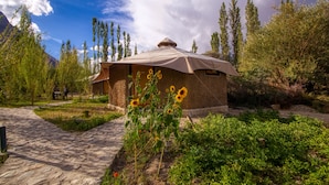 A rustic lodge with a thatched roof, surrounded by lush greenery and a stone pathway.