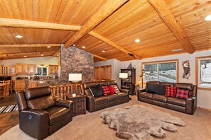 A spacious living area with leather sofas, a stone accent wall, and a large rug.