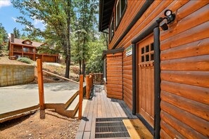A wooden cabin with a metal door, a concrete pathway, and a wooden deck.