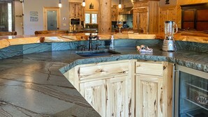 Una cocina con encimera de granito curva, armarios de madera y electrodomésticos de acero inoxidable.
