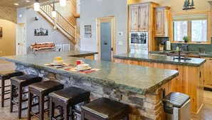 Una cocina amplia con una isla grande, taburetes de bar, horno empotrado y una pared decorativa de piedra.