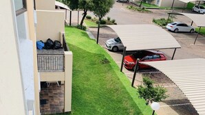 A residential area with a well-maintained lawn, parked cars, and apartment buildings in the background. - Innoprop @Midrand (Midrand)