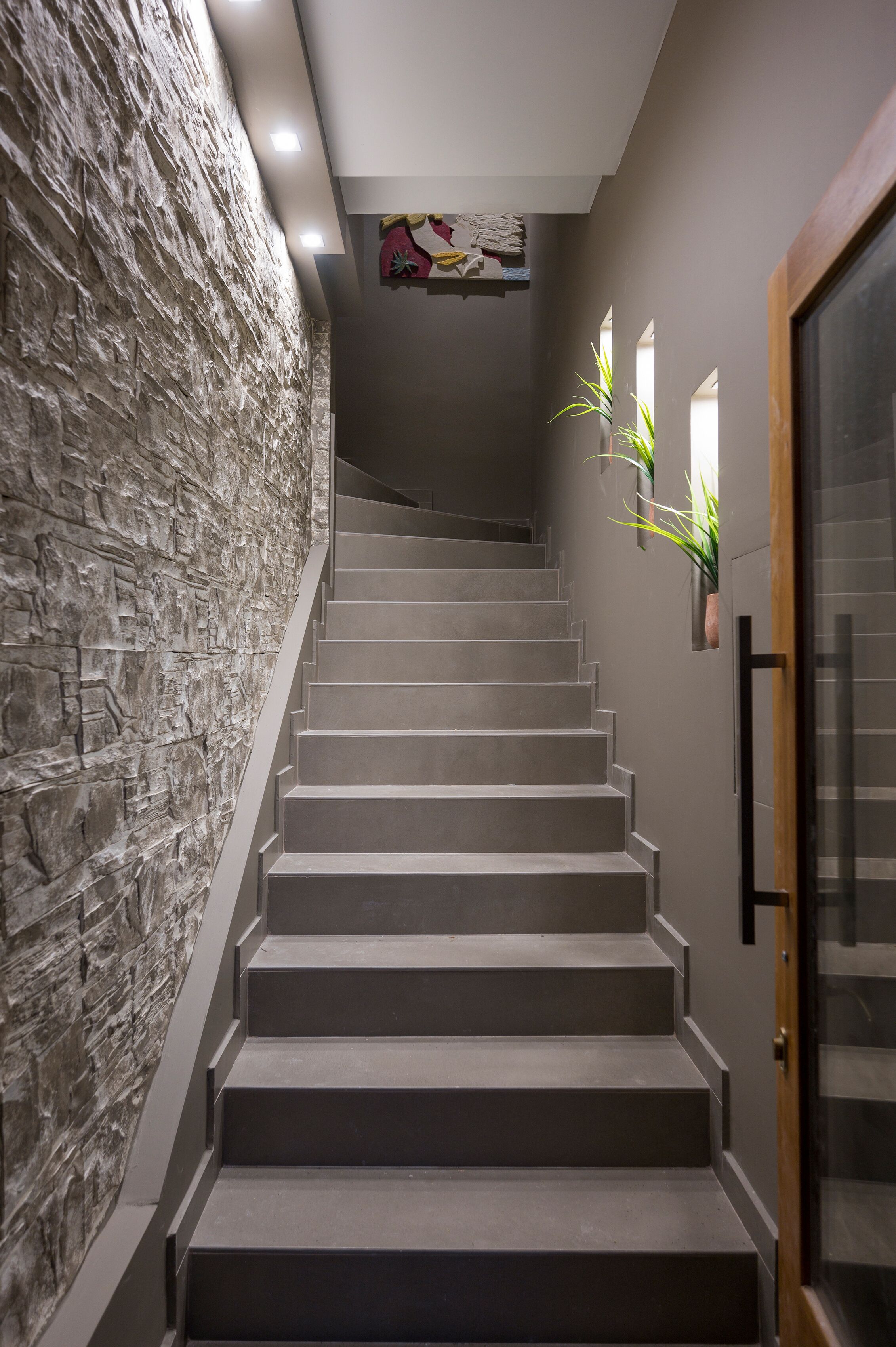 A staircase with a stone wall on one side and a door on the other.