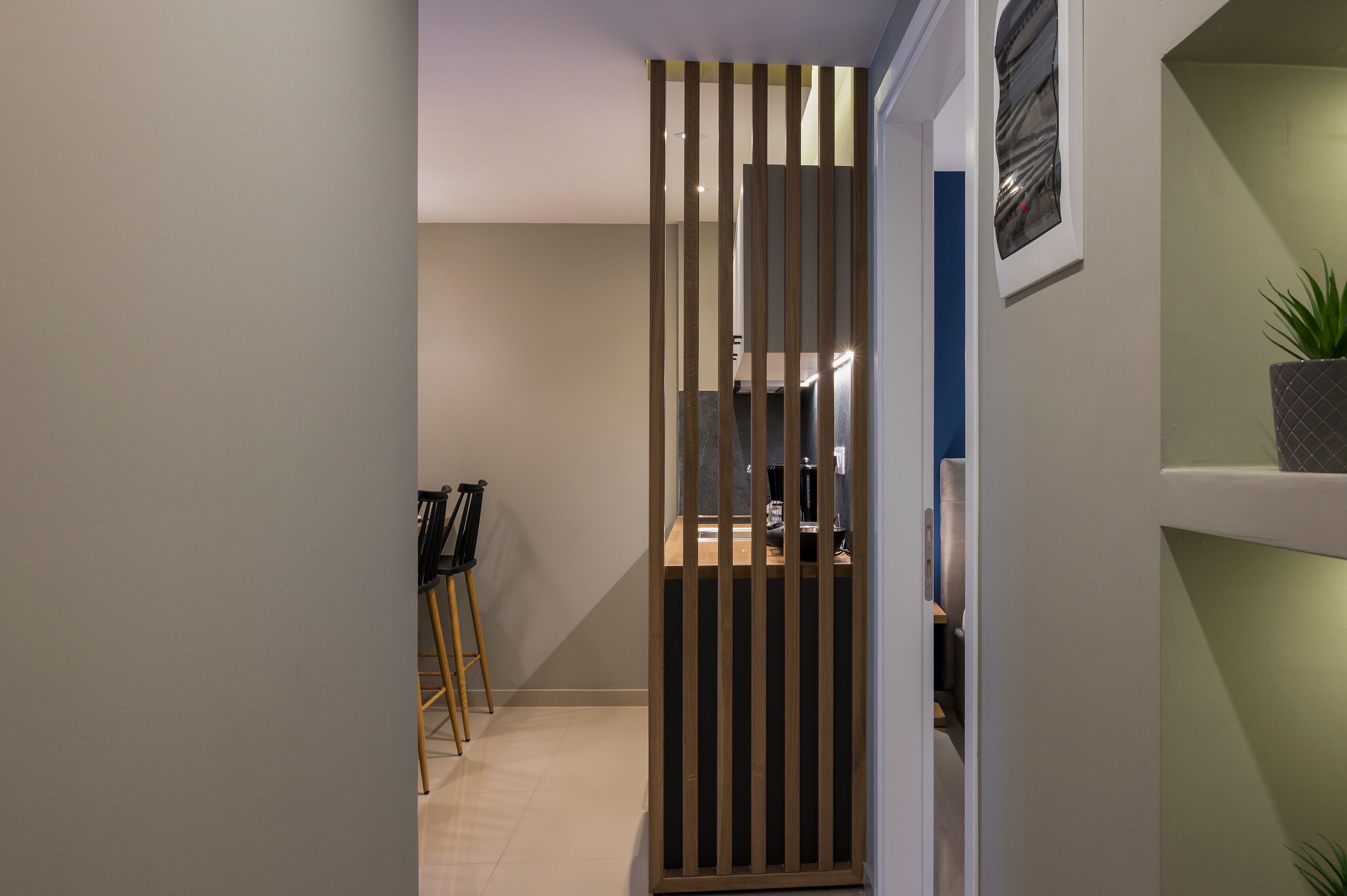 A narrow hallway with a wooden partition, a desk with a computer, and a chair.