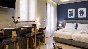 A hotel room with a bed, a desk with chairs, a TV, and artwork on the wall. -  MIRMA CITY studio & apartment (Chania)