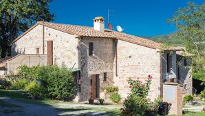 A stone building with a tiled roof, a chimney, and satellite dishes.