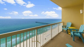 A balcony with a view of the ocean and a pier. There are two chairs and a small table. - Calypso 2003W | 20th-Floor Gulf Views, Beach Service Included, Steps from Pier Park (Panama City Beach)