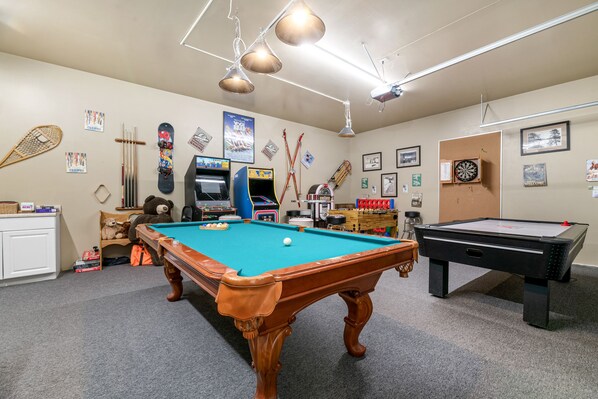 Une salle de billard équipée de deux tables de billard, d’un jeu de fléchettes et ornée de divers objets de collection liés au sport.