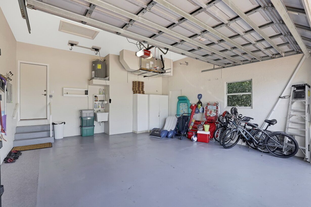 A spacious garage with a concrete floor, a door, and a ladder.