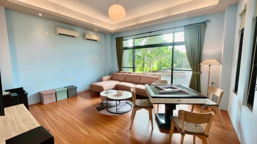 Un salón moderno con sofá, una mesa de comedor con sillas, una mesita redonda y vistas a zonas verdes.
