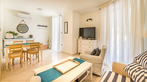 Een goed verlichte woonkamer met een televisie, bank en eethoek.