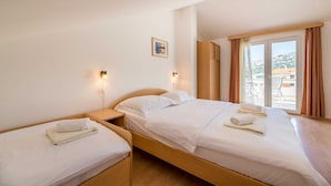 Habitación de hotel con dos camas, un ventanal con cortinas y vistas al exterior.