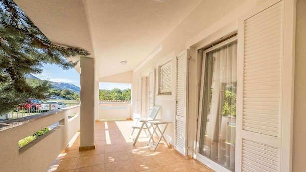 A balcony with a view of mountains, a tiled floor, and a white chair. - Extraordinary Villa Damir (Baška)
