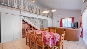 A dining area with a table set for four, a sofa, and a TV in a living area. - Extraordinary Villa Damir (Baška)