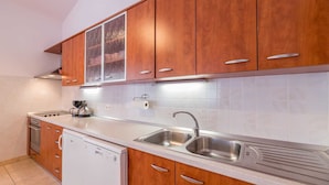 A modern kitchen with wooden cabinets, a stainless steel sink, and a dishwasher. - Extraordinary Villa Damir (Baška)