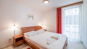 A neatly arranged bedroom with a wooden bed, bedside lamps, and a window with red curtains. - Extraordinary Villa Damir (Baška)