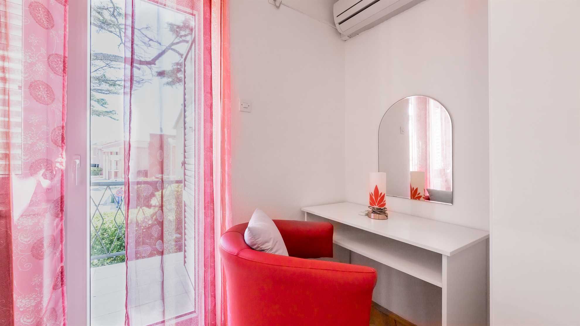 Une pièce moderne avec une chaise rouge, une console blanche et un grand miroir.