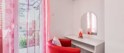 Une pièce moderne avec une chaise rouge, une console blanche et un grand miroir.