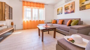 A modern living room with a sofa, a coffee table, and a TV. - Apartment Jadranka with garden and barbeque (Baška)