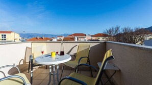 A rooftop terrace with a table and chairs, a bottle, and a glass of red wine. - Holiday apartment Tinka in centre of Baska with seaview (Baška)