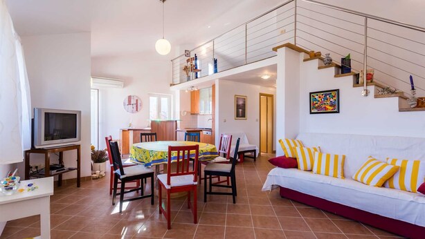 A spacious living area with a dining table, chairs, a sofa, and a TV. - Holiday apartment Tinka in centre of Baska with seaview (Baška)